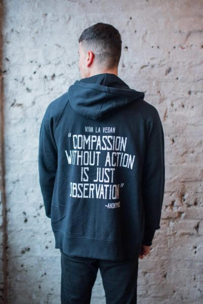 Male modle wearing eco-ethical brand Viva La Vegan's vegan activist zip hoodie "Rebel with a cause" in black.