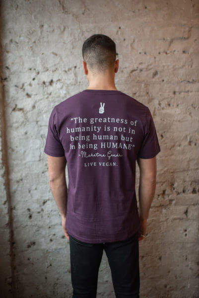 Model facing a wall and wearing a aubergine coloured t-shirt displaying the back print of Viva La Vegan "Humane Being" eco-ethical vegan t-shirt. As worn by Russel Brand.