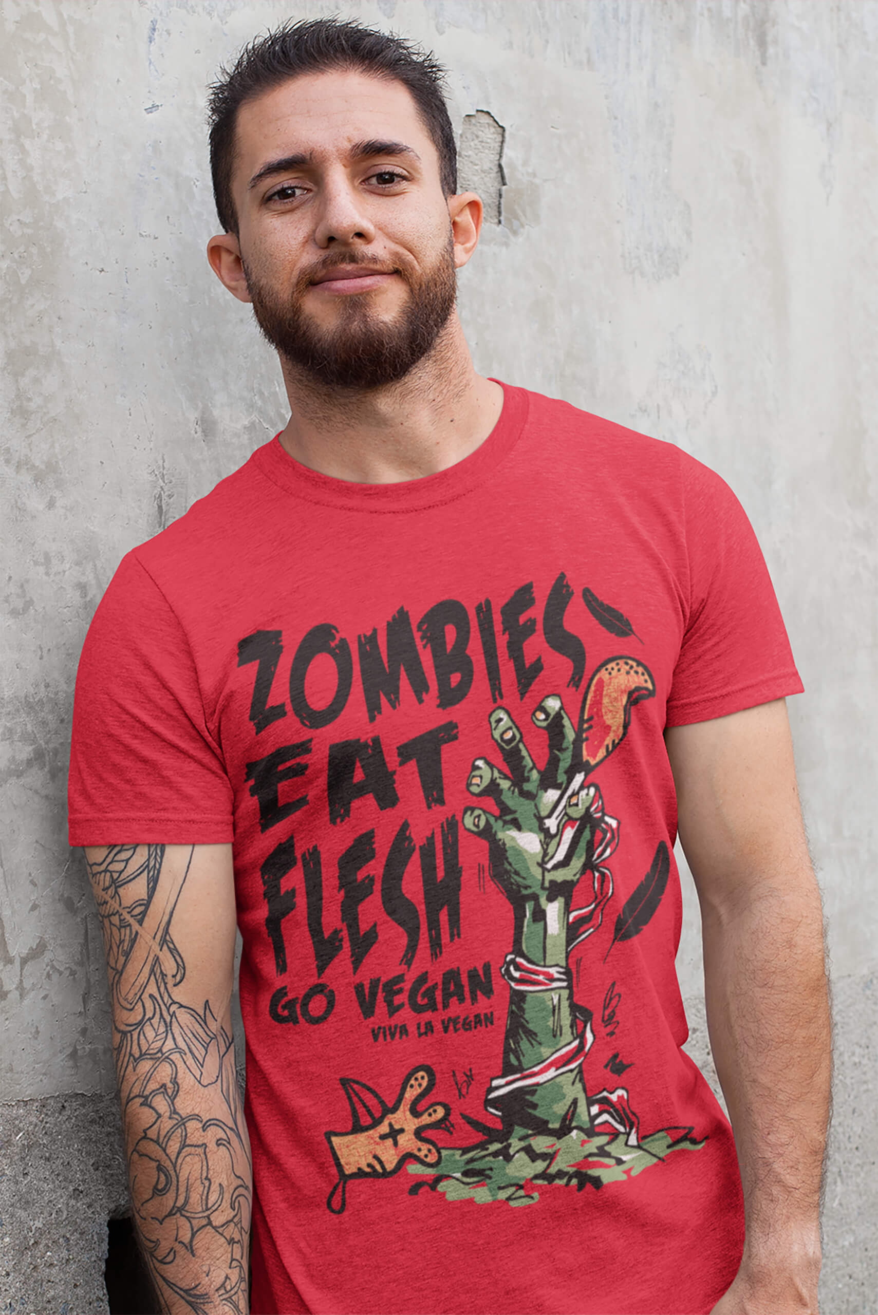 Male model standing against a wall and wearing Viva La Vegan's unisex tshirt Zombies eat flesh go vegan by viva la vegan